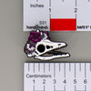 NerdyKeppie Proud to the Bone Archaeopteryx Skull Pride Enamel Pins. An archaeopteryx skull pride enamel pin for our Proud to the Bone project. This prehistoric pin is wearing an adorable crown of flowers!