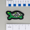 NerdyKeppie's Agender Painted Turtle Embroidered Pride Patch are shaped like their namesake and stitched on black duck cloth!