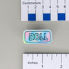 NerdyKeppie "DOLL" Mirrored Pride Pin. Mirrored pride pin with "DOLL" text in your choice of Progress, rainbow, or transgender pride colors. Say it with your whole chest.