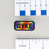 NerdyKeppie "DYKE" Mirrored Pride Pin. Mirrored pride pin with "DYKE" text, available in lesbian, Progress, or rainbow pride colors. Say it with your whole chest.