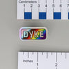 NerdyKeppie "DYKE" Mirrored Pride Pin. Mirrored pride pin with "DYKE" text, available in lesbian, Progress, or rainbow pride colors. Say it with your whole chest.