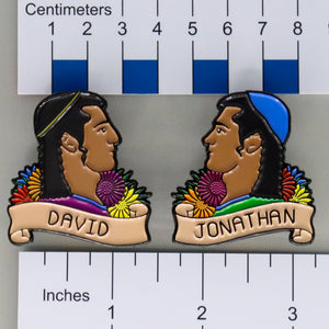 NerdyKeppie David & Jonathan Historically Queer Pride Enamel Pin. Our NerdyKeppie Historically Queer Pride enamel pin features David & Jonathan surrounded by stylized wildflowers and olive leaves in rainbow gay pride colors. This pride pin ships from Portland, Oregon.