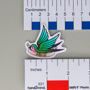 NerdyKeppie Faygele Little Bird Pride Sticker. Our little bird stickers feature an american traditional tattoo-style sparrow carrying a banner that reads faygele in Yiddish. Each of our little bird stickers ships from Portland, Oregon.