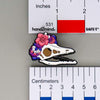 NerdyKeppie Proud to the Bone Archaeopteryx Skull Pride Enamel Pins. An archaeopteryx skull pride enamel pin for our Proud to the Bone project. This prehistoric pin is wearing an adorable crown of flowers!