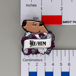 NerdyKeppie Capybara Enamel Ace Pride Pronoun Pins. Our enamel pin features an adorable capybara, a paper scroll with five different pronoun choices, and flowers in asexual pride colors. This pride pin ships from Portland, Oregon.