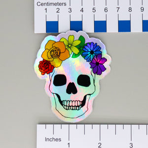 NerdyKeppie Human Skull Rainbow Gay Pride Holographic Stickers. Our NerdyKeppie Human Skull Rainbow Gay Pride Holographic Stickers are 3" x 2.5" vinyl stickers of a human ribcage festooned with festive flowers in the colors of the rainbow pride flag. Just the thing for the queer goth anthropologist in your life.