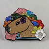 NerdyKeppie Keppiebara Progress Pride Enamel Pin. A pride enamel pin featuring a capybara with progress pride color flowers around the adorable beast. This pin is glittery!