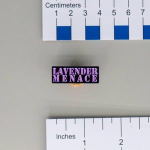 NerdyKeppie "Lavender Menace" Enamel Pin. A black metal pin with lavender stencil text on it reading LAVENDER MENACE. Perfect for queers who scare cishet feminists?