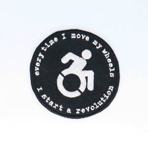NerdyKeppie's No Hooked Backing "Every Time I Move My Wheels I Start A Revolution" Embroidered Disability Pride Patch are stitched on black duck cloth and backed by sturdy vinyl fuse.