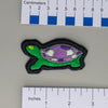 NerdyKeppie's Painted Turtle Embroidered Pride Patch are shaped like their namesake and stitched on black duck cloth!