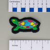 NerdyKeppie's Pan Painted Turtle Embroidered Pride Patch are shaped like their namesake and stitched on black duck cloth!