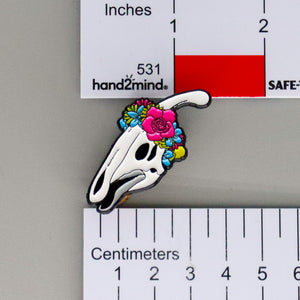NerdyKeppie Proud to the Bone Parasauralophus Skull Pride Enamel Pins. A Parasauralophus skull pride enamel pin for our Proud to the Bone project. This prehistoric pin is wearing an adorable crown of flowers!