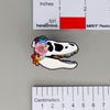 NerdyKeppie Proud to the Bone Tyrannosaurus Rex Skull Pride Enamel Pins. A Tyrannosaurus Rex skull pride enamel pin for our Proud to the Bone project. This prehistoric T-Rex pin is wearing an adorable crown of flowers!
