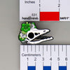 NerdyKeppie Proud to the Bone Archaeopteryx Skull Pride Enamel Pins. An archaeopteryx skull pride enamel pin for our Proud to the Bone project. This prehistoric pin is wearing an adorable crown of flowers!