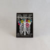 NerdyKeppie Proud to the Bone Human Ribcage Pride Enamel Pins. A human ribcage pride enamel pin for our Proud to the Bone project, wearing an adorable crown of flowers!