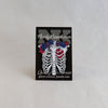 NerdyKeppie Proud to the Bone Human Ribcage Pride Enamel Pins. A human ribcage pride enamel pin for our Proud to the Bone project, wearing an adorable crown of flowers!