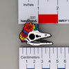 NerdyKeppie Proud to the Bone Archaeopteryx Skull Pride Enamel Pins. An archaeopteryx skull pride enamel pin for our Proud to the Bone project. This prehistoric pin is wearing an adorable crown of flowers!