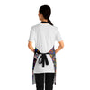 A person wearing a NerdyKeppie Stencil Roses Progress Pride Apron With Pocket. A black apron with a stencil roses design on it in progress pride colors. This gay pride pocket apron is made of durable 100% polyester.