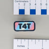 NerdyKeppie "T4T" Mirrored Pride Pin. Mirrored pride pin with "T4T" text, available in genderfluid, non-binary, Progress, rainbow, or trans pride colors. Say it with your whole chest.