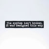 NerdyKeppie's "The System Isn't Broken It Was Designed This Way" Embroidered Patch are stitched on sturdy rectangular duck cloth and backed with vinyl fuse.