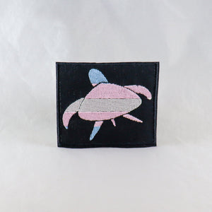 NerdyKeppie's Trans Sea Turtle Embroidered Pride Patch are shaped like their namesake and stitched on black duck cloth!