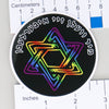 NerdyKeppie "We Will Outlive Them" Monochrome & Rainbow Gay Pride Judaica Stickers. A NerdyKeppie matte sticker reading "We Will Outlive Them" in Yiddish, above a Star of David in your choice of rainbow gradient or plain white. This Judaica sticker ships from Portland, Oregon.