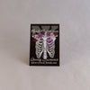 NerdyKeppie Proud to the Bone Human Ribcage Pride Enamel Pins. A human ribcage pride enamel pin for our Proud to the Bone project, wearing an adorable crown of flowers!