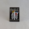 NerdyKeppie Proud to the Bone Human Ribcage Pride Enamel Pins. A human ribcage pride enamel pin for our Proud to the Bone project, wearing an adorable crown of flowers!